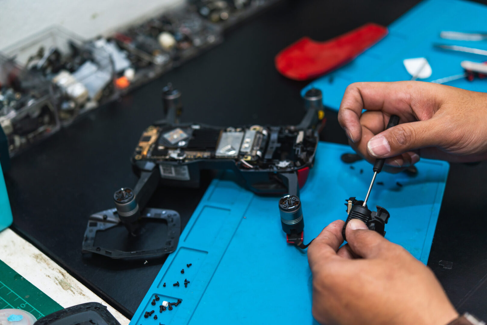 Concentrated man repairing drone detail with screwdriver